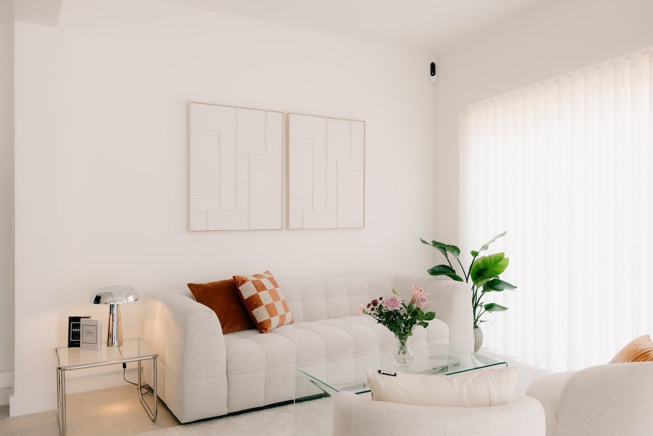 Loungehoek met zetel, cognac kussens, plant en lichte gordijnen